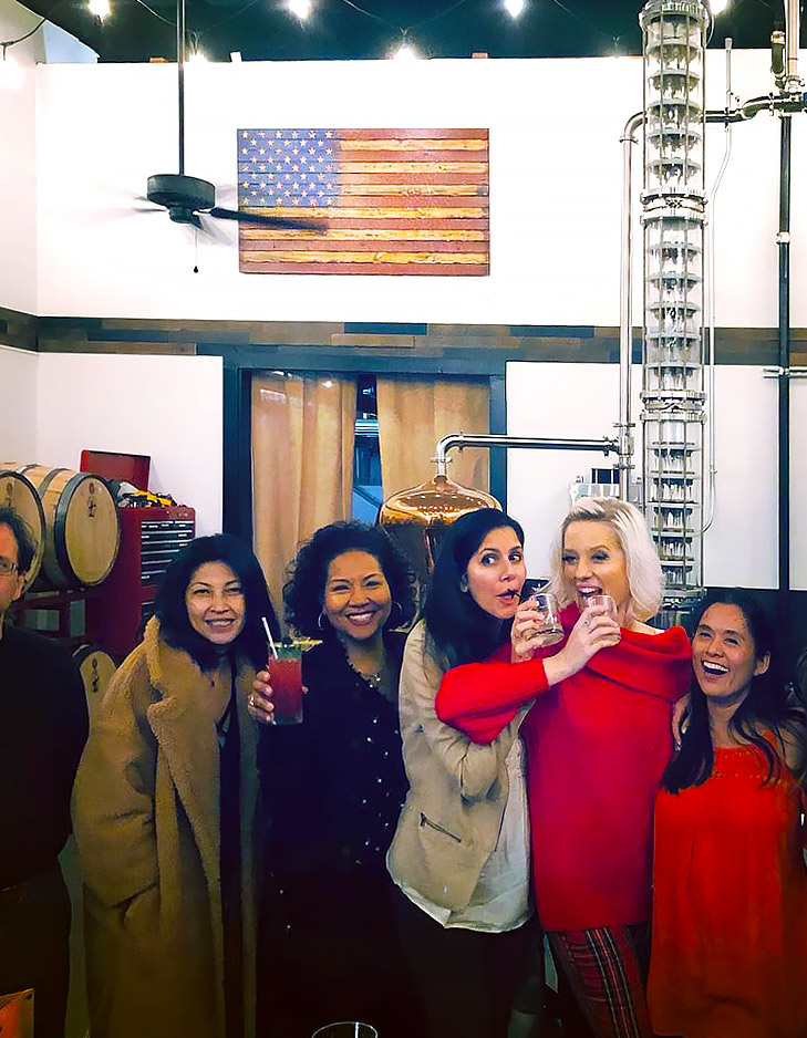 image of a group of friends at the distillery smiling with drinks in hand 